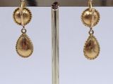 pair of gold tone earrings with dangling drops on a gold plated stand