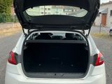 the back of a white car with its trunk open in a parking lot