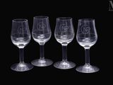 quatre verres à vin vides empilés les uns sur les autres sur une surface noire