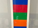 a multicolored vase on a white stand on a table