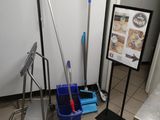 a blue mop and a blue bucket on the floor next to a sign