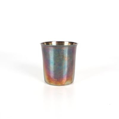 une tasse en métal posée sur une surface blanche