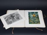 an open book sitting on top of a table next to two pictures