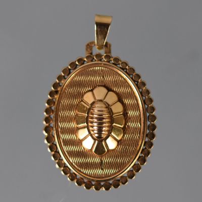 un gros plan d'un pendentif en or orné d'une abeille