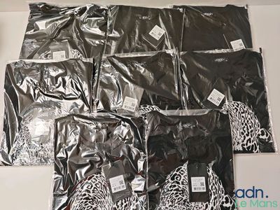 plusieurs sacs contenant des vêtements noirs et blancs posés sur une table