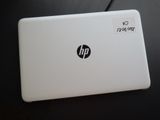 un ordinateur portable blanc, sur lequel est collé un autocollant, posé sur une table