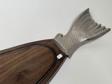 wooden paddle with a fish shaped handle sitting on top of a white surface