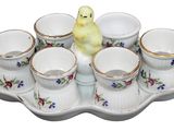 a small yellow bird sitting on a tray with cups