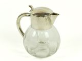 un pichet en verre muni d'une anse en métal, sur fond blanc