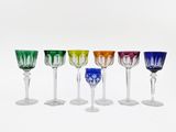 several different colored wine glasses sitting on top of a white surface