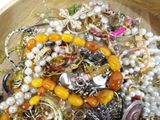 a wooden bowl filled with lots of assorted jewelry