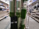 Plusieurs rouleaux de gazon synthétique sont empilés les uns sur les autres dans un magasin