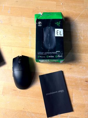 une souris noire et une boîte noire posées sur une table en bois