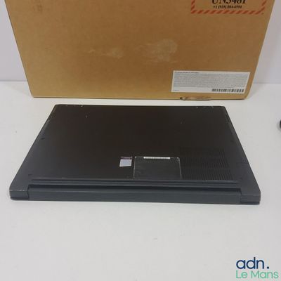 un ordinateur portable noir posé sur une table à côté d'une boîte