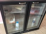 un petit réfrigérateur avec une porte en verre, sur lequel est posé un cupcake