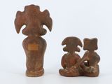 two small figurines of a woman and a dog sitting on a white surface