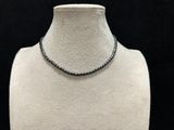 a white mannequin with a black beaded necklace on it
