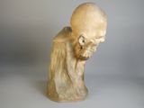 statue d'un homme chauve assis sur une surface blanche