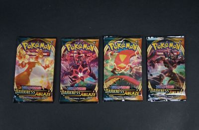 trois paquets de cartes à collectionner Pokémon posés sur une surface noire