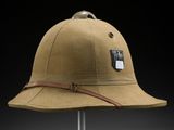 a brown hat on a metal stand against a black background