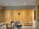 a room with a table, chairs, and many glasses on the wall