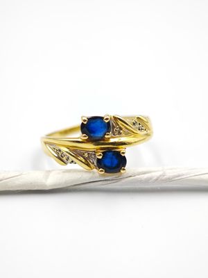 un gros plan d'une bague en or sertie de deux pierres bleues