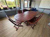 une table et des chaises en bois dans une pièce dotée de grandes fenêtres