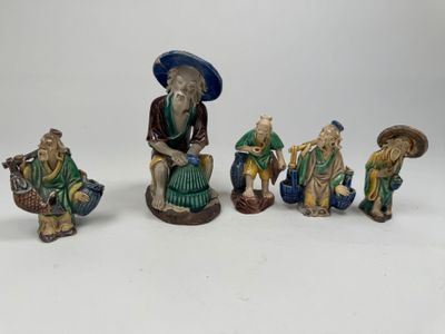 quatre figurines représentant des personnages asiatiques assis sur une surface blanche