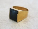 une image représentant une bague en or sertie d'une pierre noire