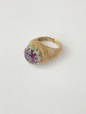 a close up of a gold ring with a purple stone