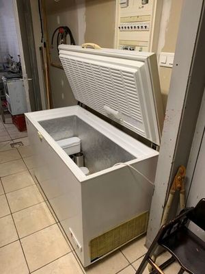un congélateur coffre blanc posé dans une cuisine, à côté d'une chaise