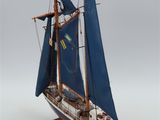 wooden model of a sailboat with blue sails on a wooden stand
