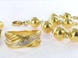 un bracelet en or, une bague et d'autres bijoux posés sur une surface blanche