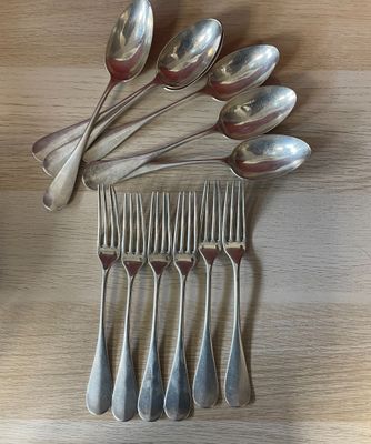 un grand nombre de cuillères et de fourchettes disposées sur une table