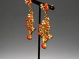 pair of gold and coral earrings on a black stand