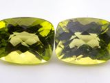 two square cut green and yellow gems on a white surface