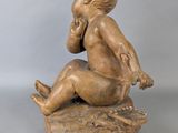 statue of a boy sitting on a rock with his hand on his chin