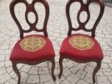 pair of antique chairs with red upholstered seats on a brick patio
