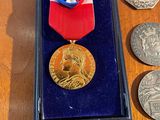 a medal in a box surrounded by coins on a table