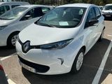 une voiture blanche garée sur un parking, avec d'autres voitures en arrière-plan