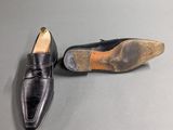 pair of men ' s black leather shoes on a grey surface
