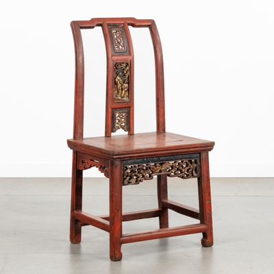 une chaise en bois dont le dossier et l'assise sont sculptés, dans une pièce