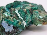 a close up of a piece of green mineral on a white surface