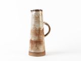 a brown and white vase with a handle on a white surface