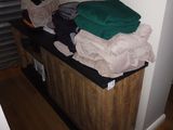 a pile of clothes sitting on top of a wooden cabinet