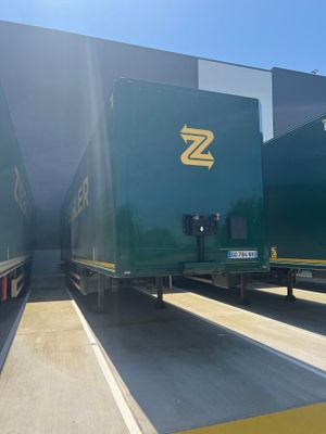 deux semi-remorques verts garés sur un parking, baignés par la lumière du soleil