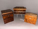 Trois petites boîtes en bois sont posées les unes à côté des autres sur une table