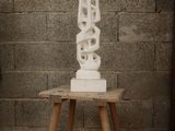 a white sculpture sitting on a wooden table in front of a brick wall