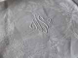a close up of a white table cloth with a monogram on it