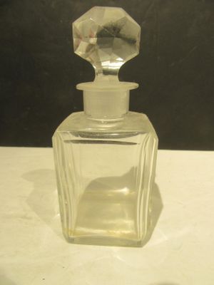 une petite bouteille en verre avec un bouchon transparent, posée sur une table